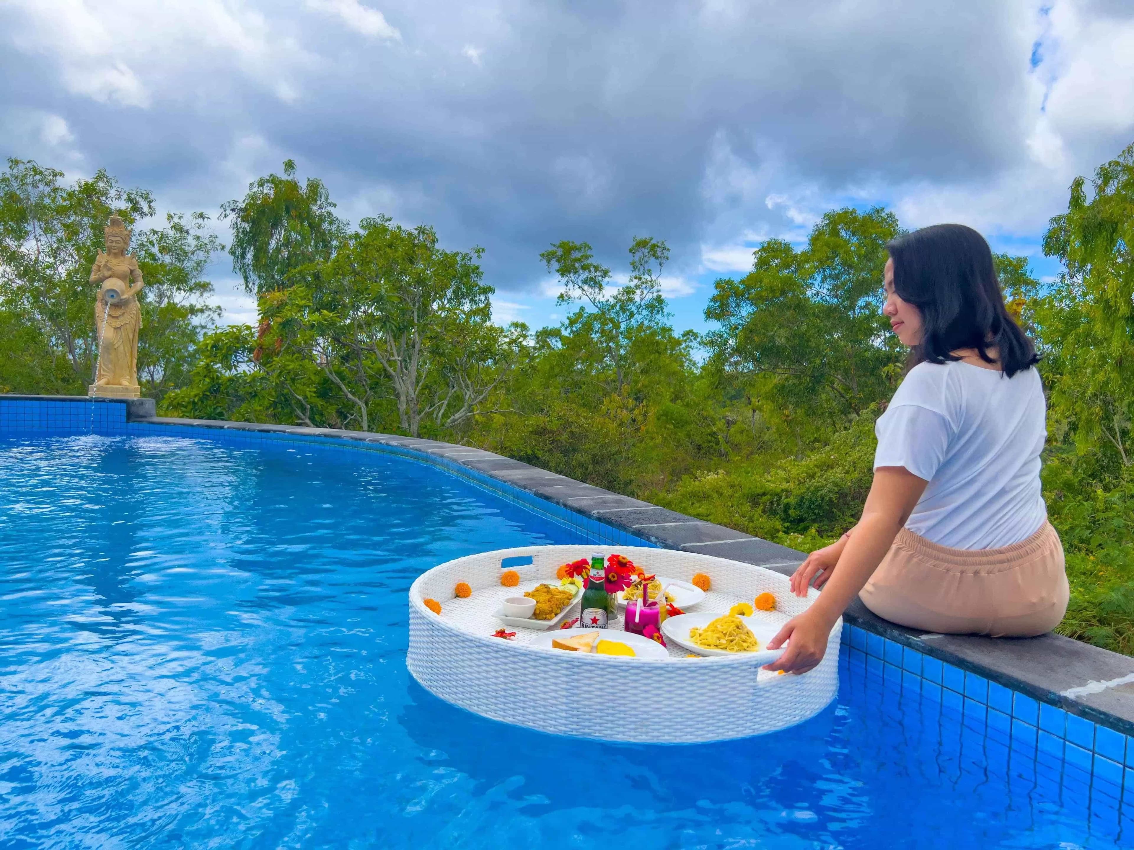 Woman with floating breakfast tray at the pool edge