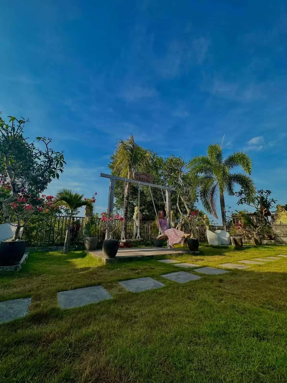 Guest on garden swing with lush tropical garden